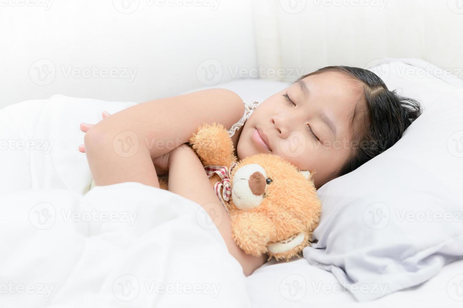 cute girl sleep and hug teddy bear on bed photo