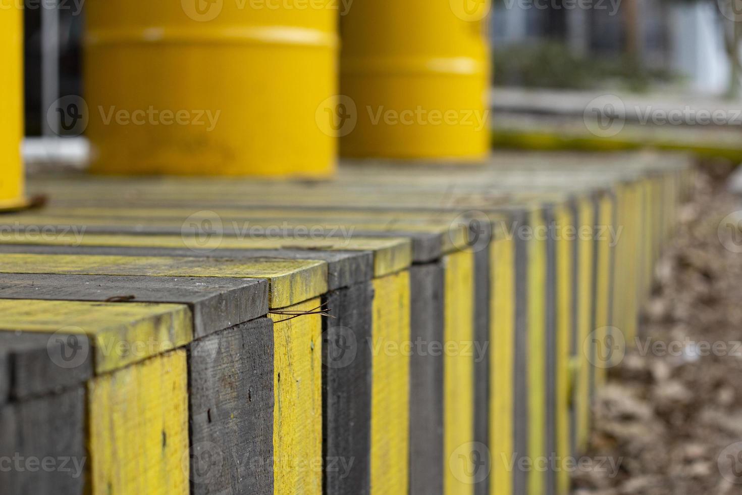 Yellow barrels on a wooden fence in the street. Yellow barrels of oil on the background of a row of yellow and black fences. photo