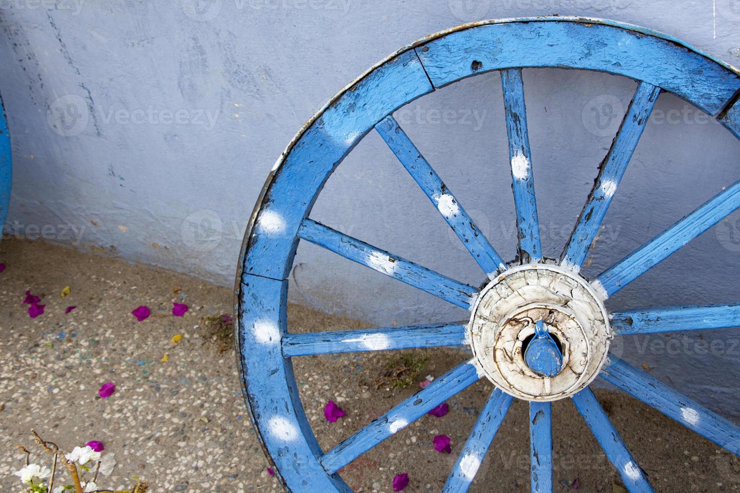 Old wooden blue wheel, close up view of the wheel. The old wooden wheel on the background of the blue wall of the house photo