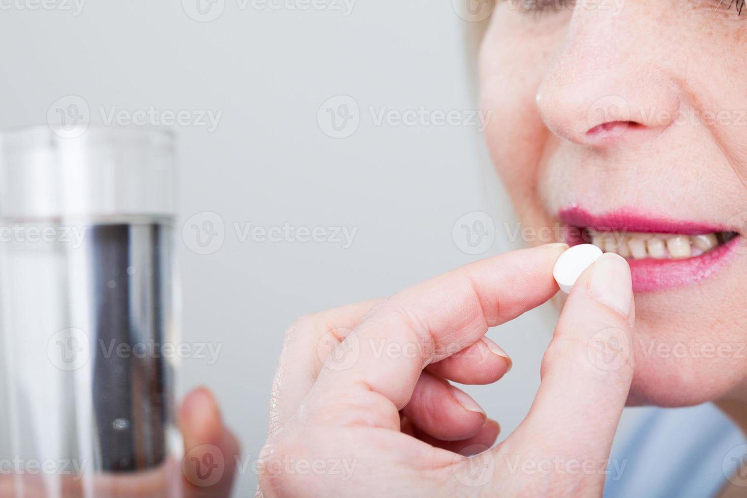 Sick frustrated woman feel unwell holding glass of water and pill doubting to take medicine, exhausted female suffer from migraine or headache ready to have antibiotic or painkiller to ease symptoms photo