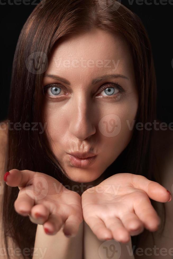 Adult woman blowing lips send air kiss over palms to her boyfriend and looking at camera photo