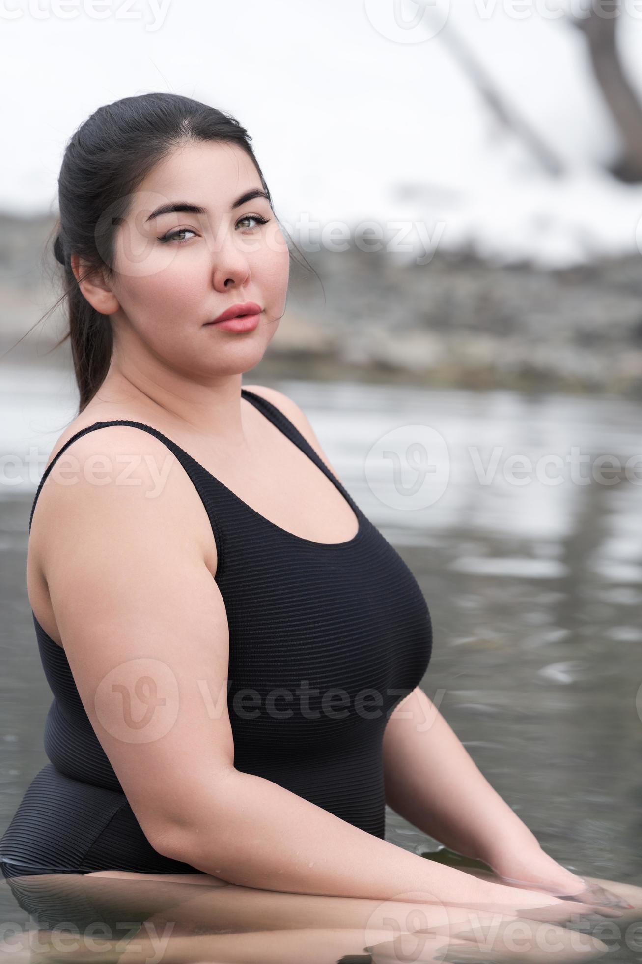 Young busty curvy full figured young model in black swimsuit sitting in  outdoors pool at spa resort 21791929 Stock Photo at Vecteezy