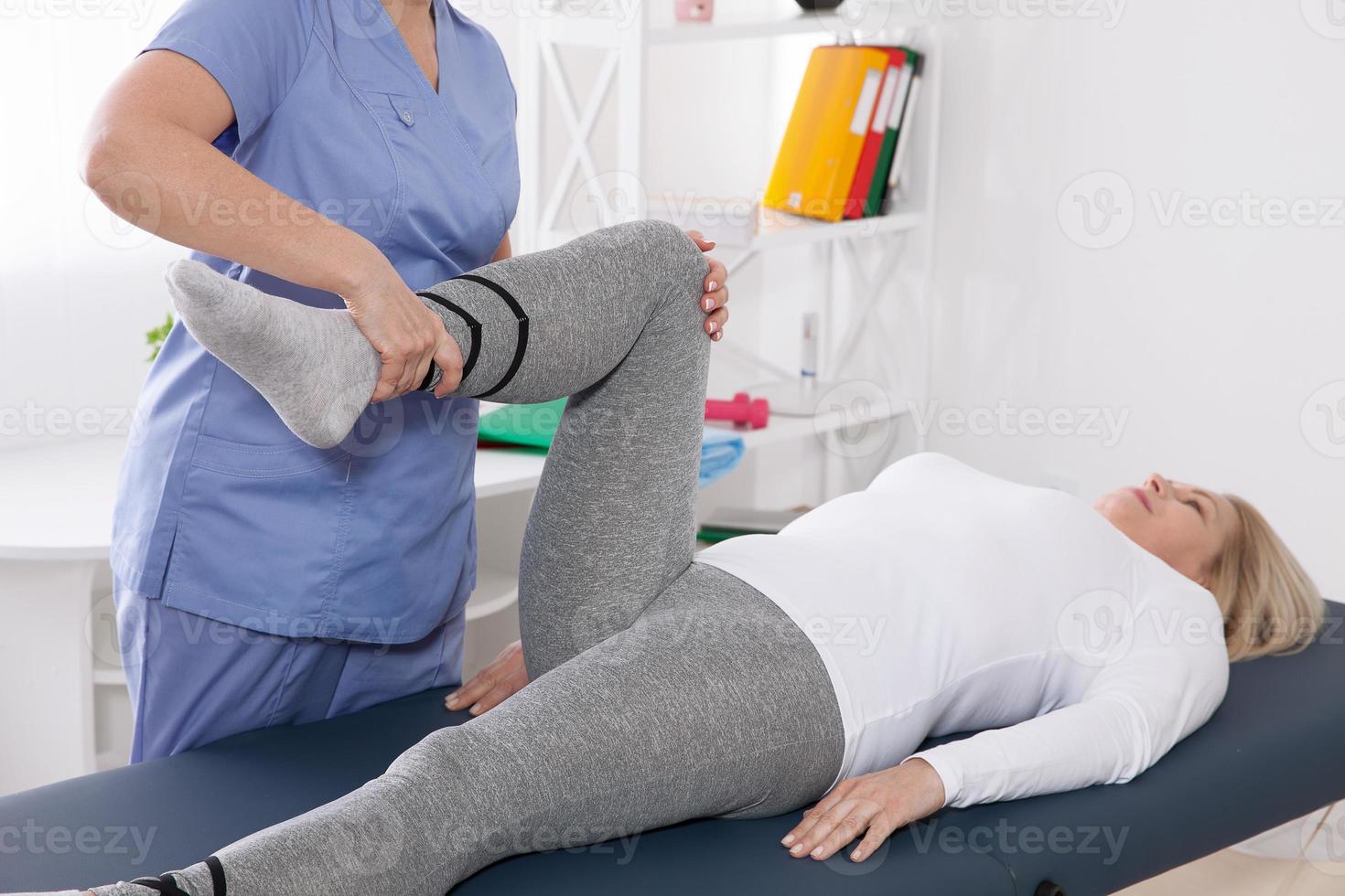 primer plano de la fisioterapeuta femenina masajeando la pierna del paciente en una sala de fisioterapia. foto