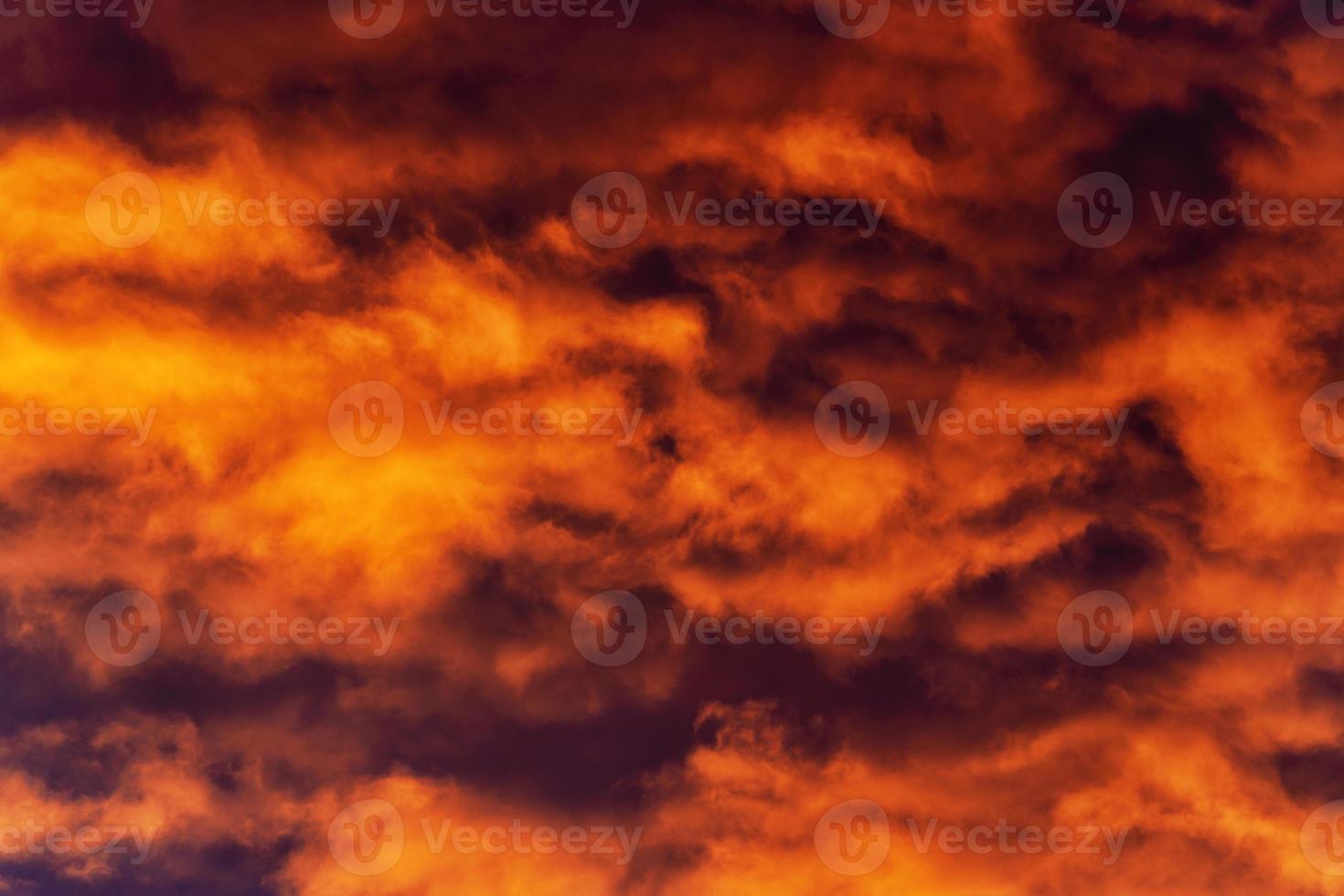 Golden clouds at sunset floating across violet and purple thunderclouds in sky photo