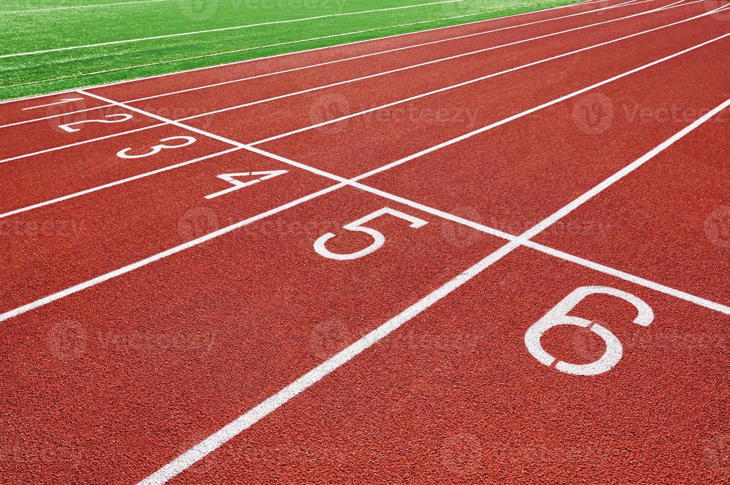 Red running track at stadium with lane numbers photo