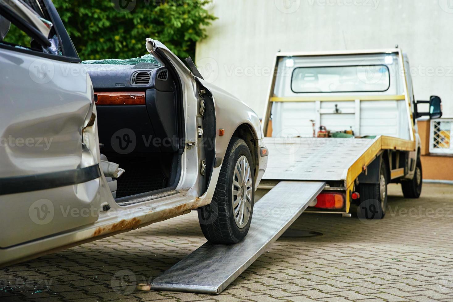 Crashed car loading into tow truck after traffic accident on road photo