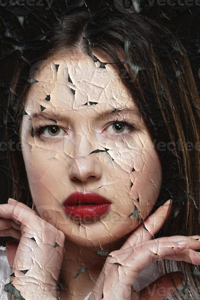 Portrait of a beautiful girl with red lips on a background of torn and crumpled paper. photo