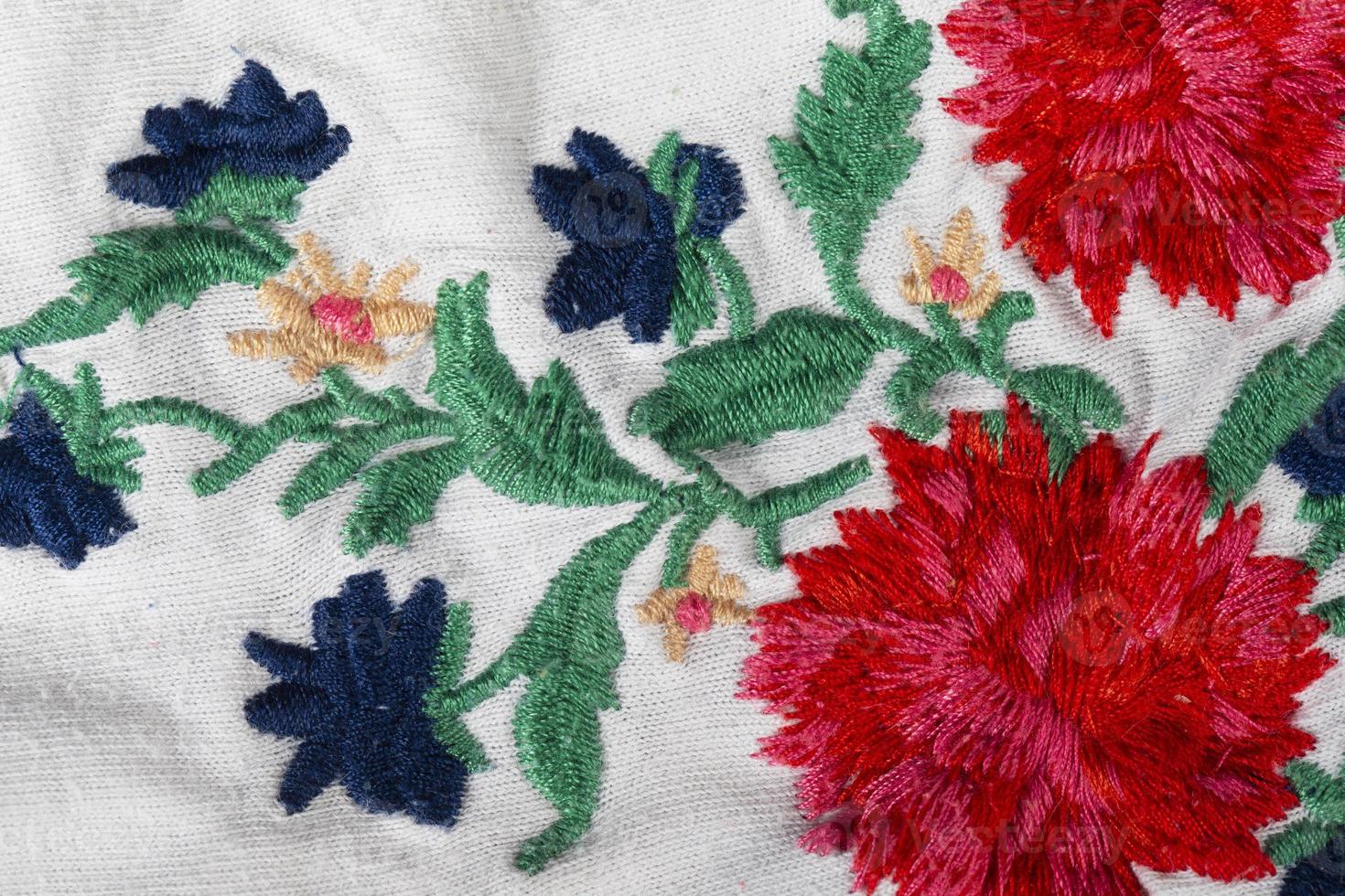 A piece of white cotton fabric with embroidered bright flowers. photo