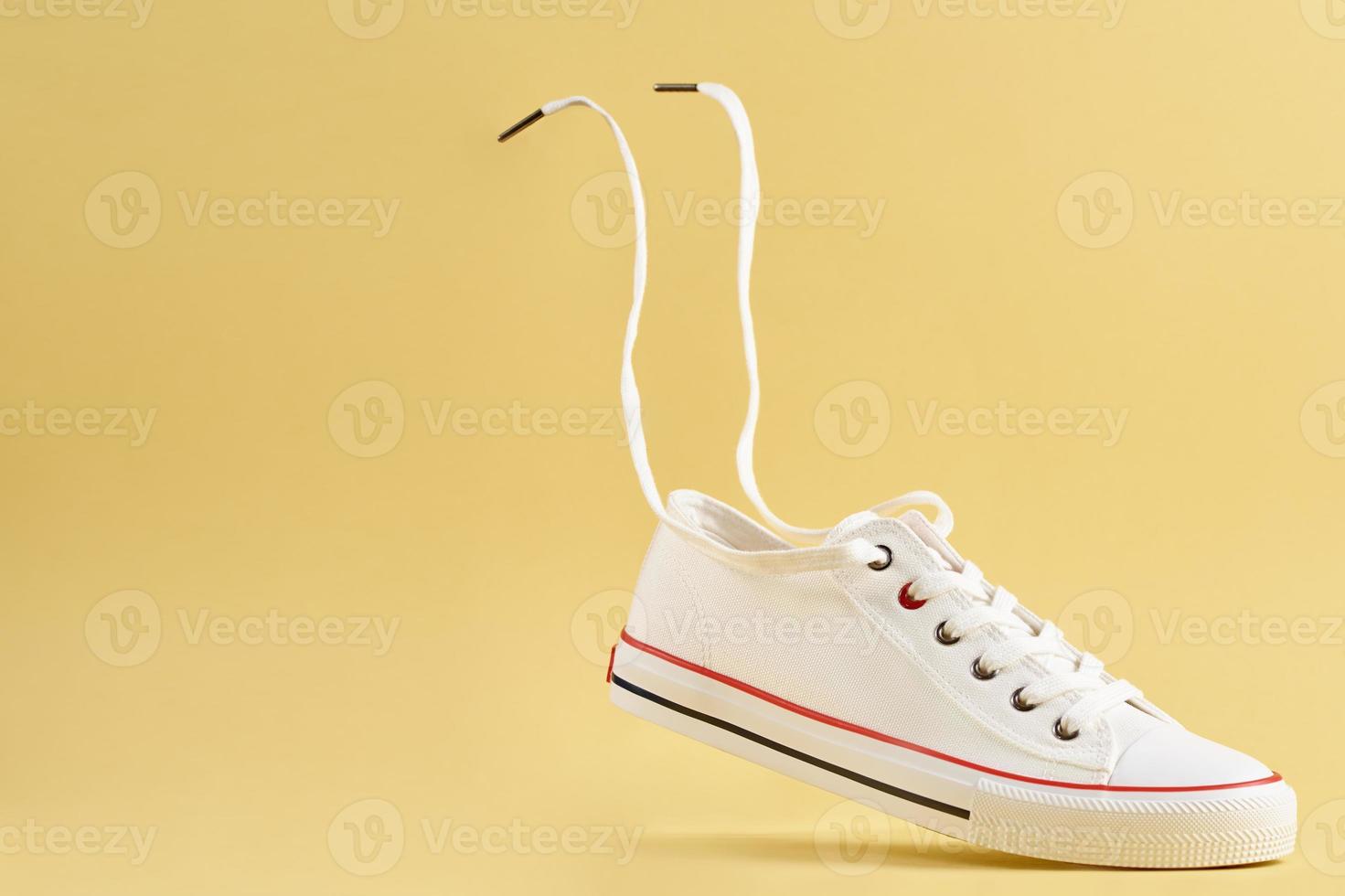 White casual sneakers on yellow background, creative minimalism photo