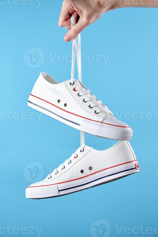 White casual sneakers on blue background, creative minimalism photo