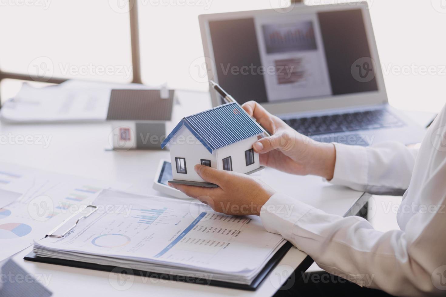 modelo de casa con agente de bienes raíces y cliente discutiendo por contrato para comprar casa, seguro o fondo de préstamo de bienes raíces. foto