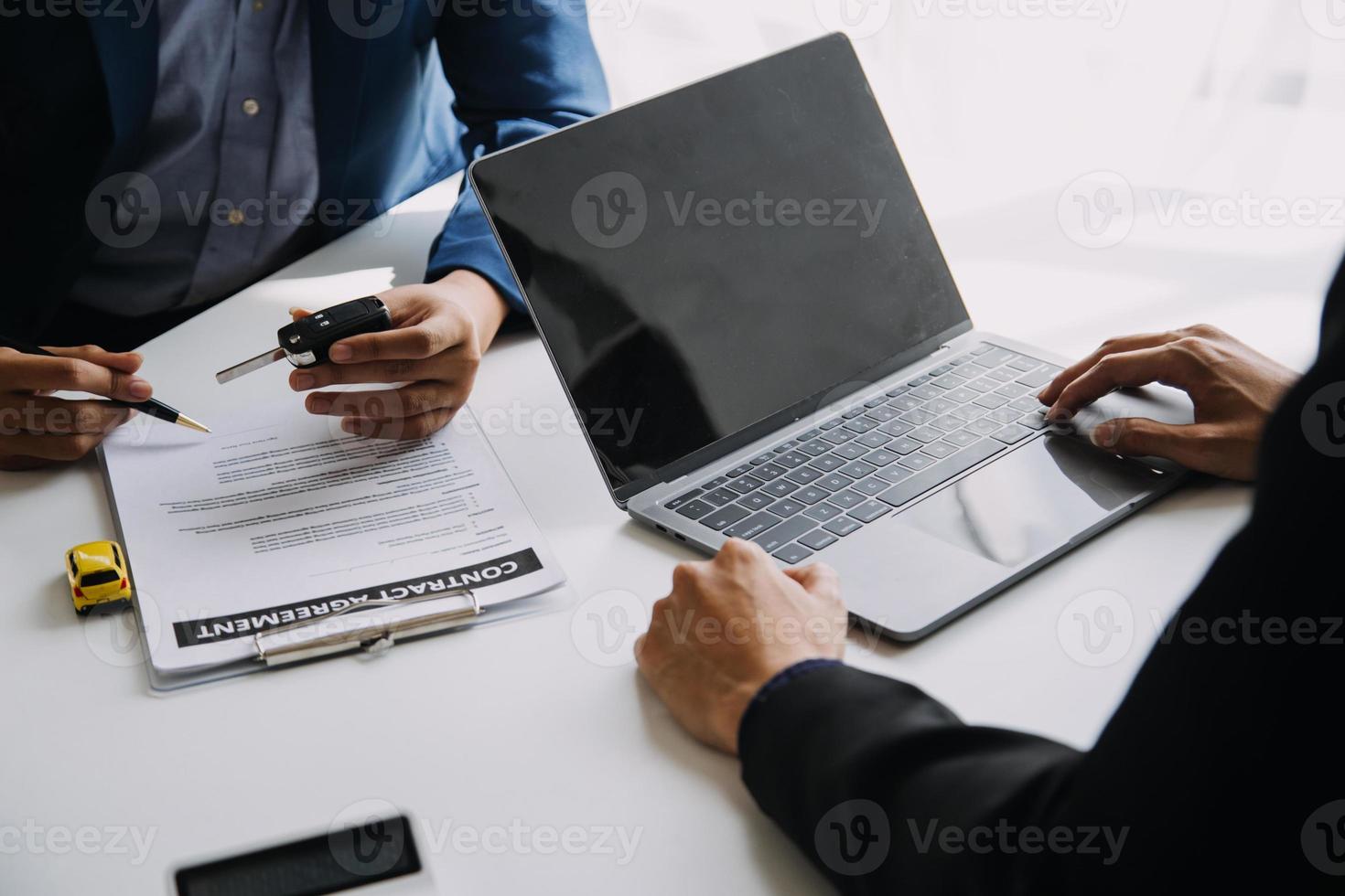 A car rental company employee is handing out the car keys to the renter after discussing the rental details and conditions together with the renter signing a car rental agreement. Concept car rental. photo