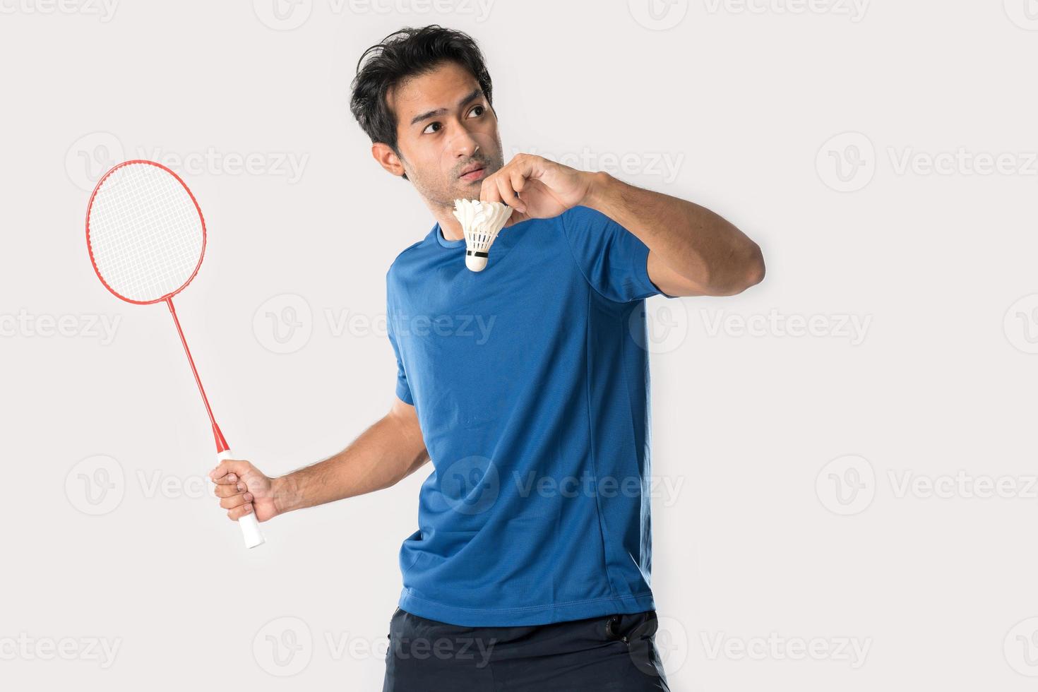 A badminton player in sportswear stands holding a racket and shuttlecock. photo