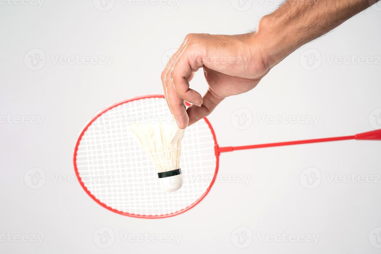 A badminton player in sportswear stands holding a racket and shuttlecock. photo