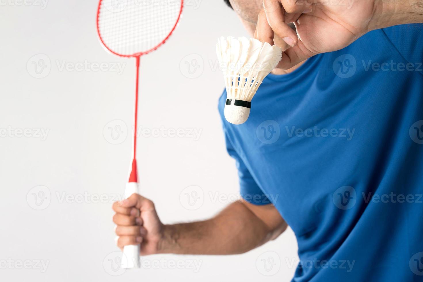 A badminton player in sportswear stands holding a racket and shuttlecock. photo