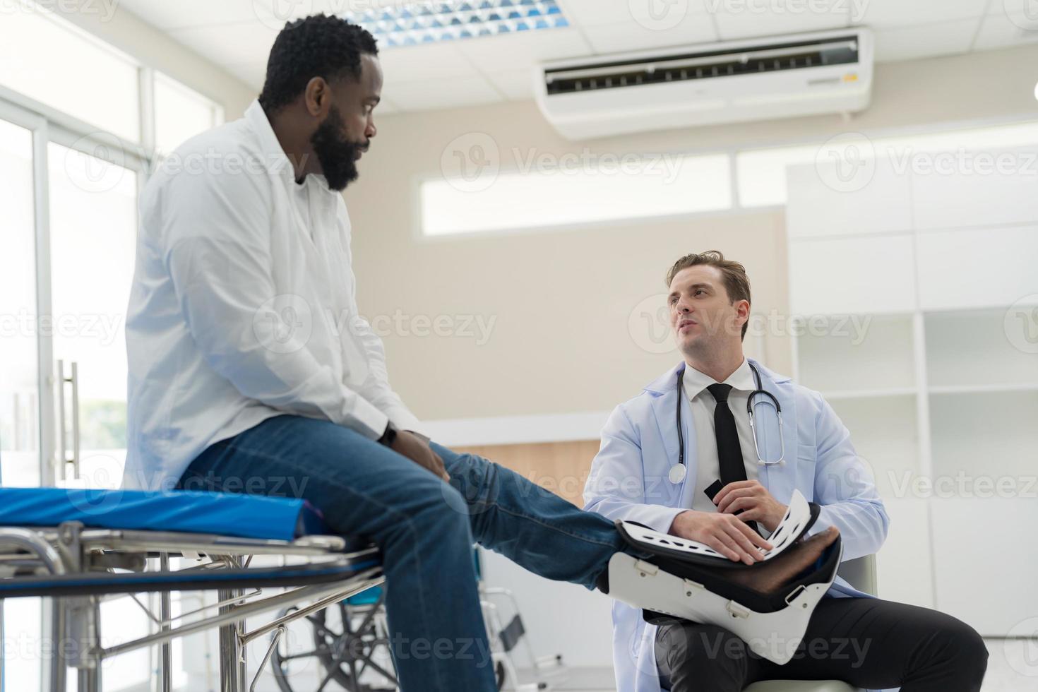 el médico pone un entablillar en un paciente con un pierna. foto