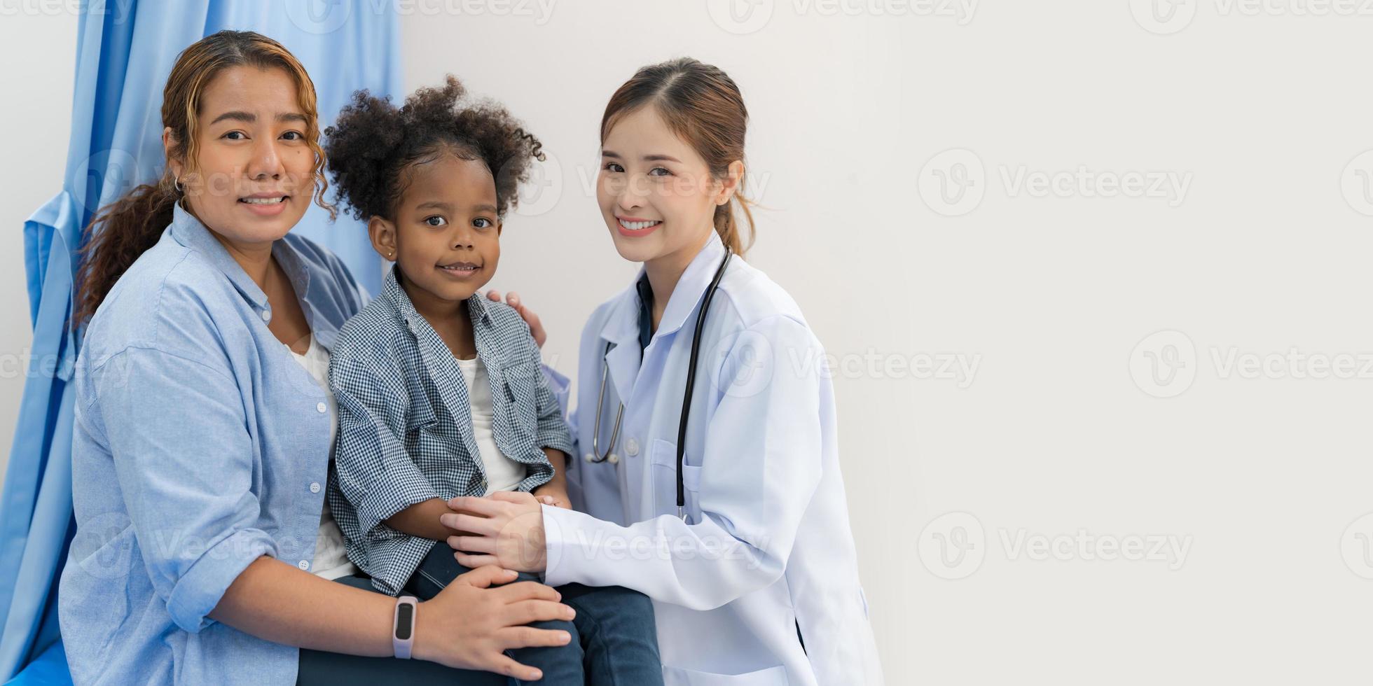 el niña se sienta en el del paciente cama para el doctor. foto