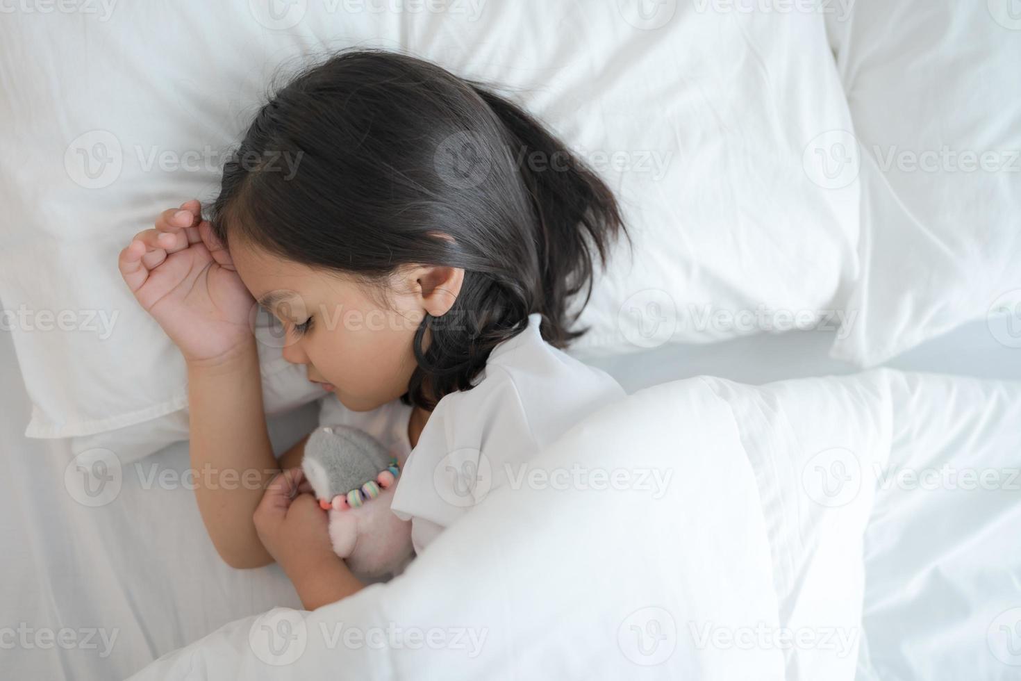 The girl sleeps in a comfortable white bedroom. photo