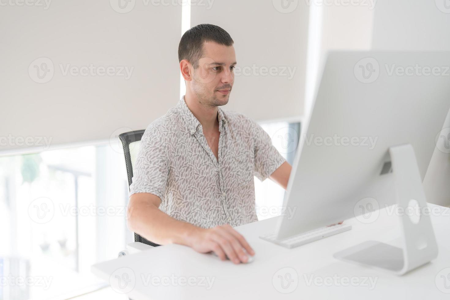 joven hombre utilizando computadora mientras sentado en silla. foto