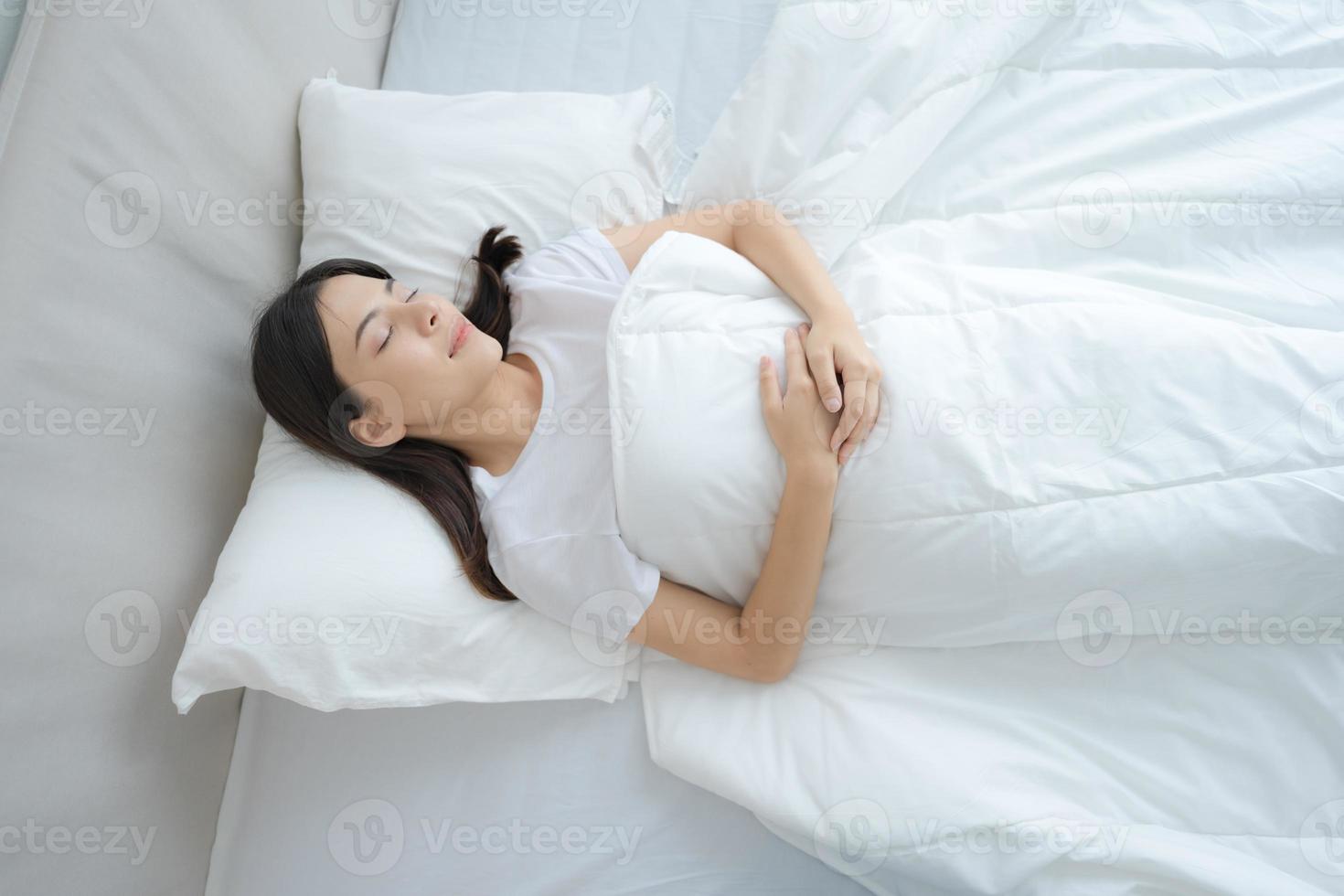 Young woman sleeping in a comfortable white bedroom. photo