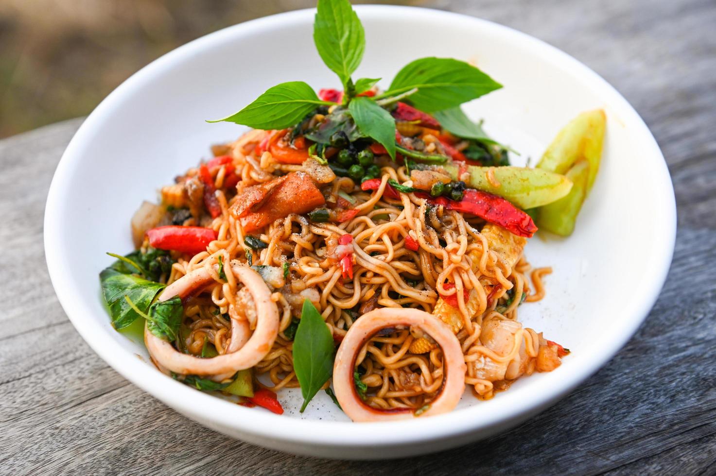noodles plate with instant noodles stir fried with vegetables herb spicy tasty appetizing asian noodles mix seafood stir fried squid with basil and chilli pepper photo