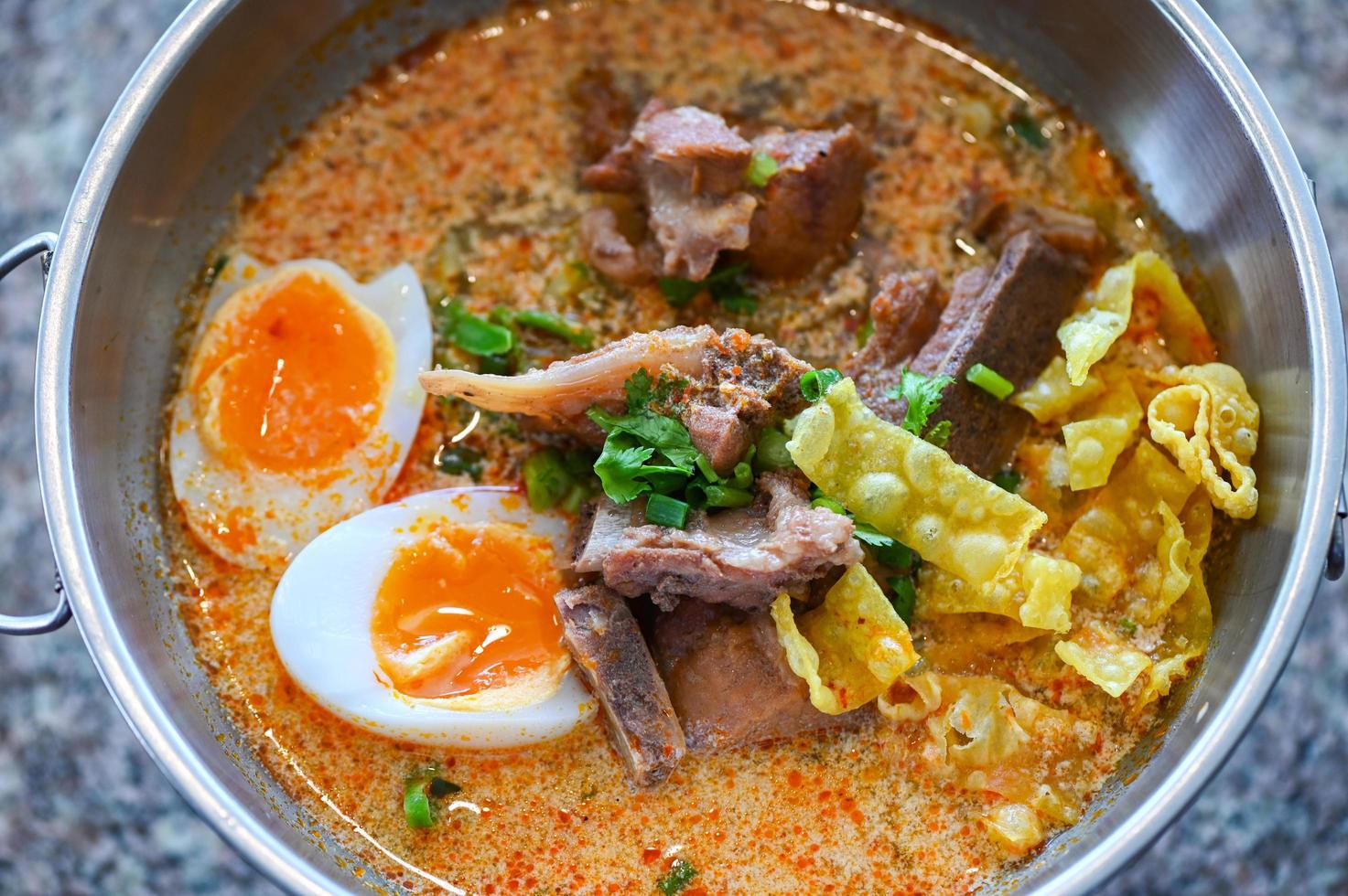 curry bone soup - bone soup pork with boiled eggs in hot pot, Thai food tom yum hot and sour soup photo