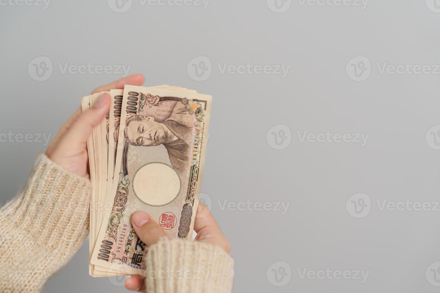 mano de mujer sosteniendo la pila de billetes de yen japonés. dinero de mil yenes. conceptos de pago en efectivo, impuestos, economía de recesión, inflación, inversión, finanzas y compras de japón foto