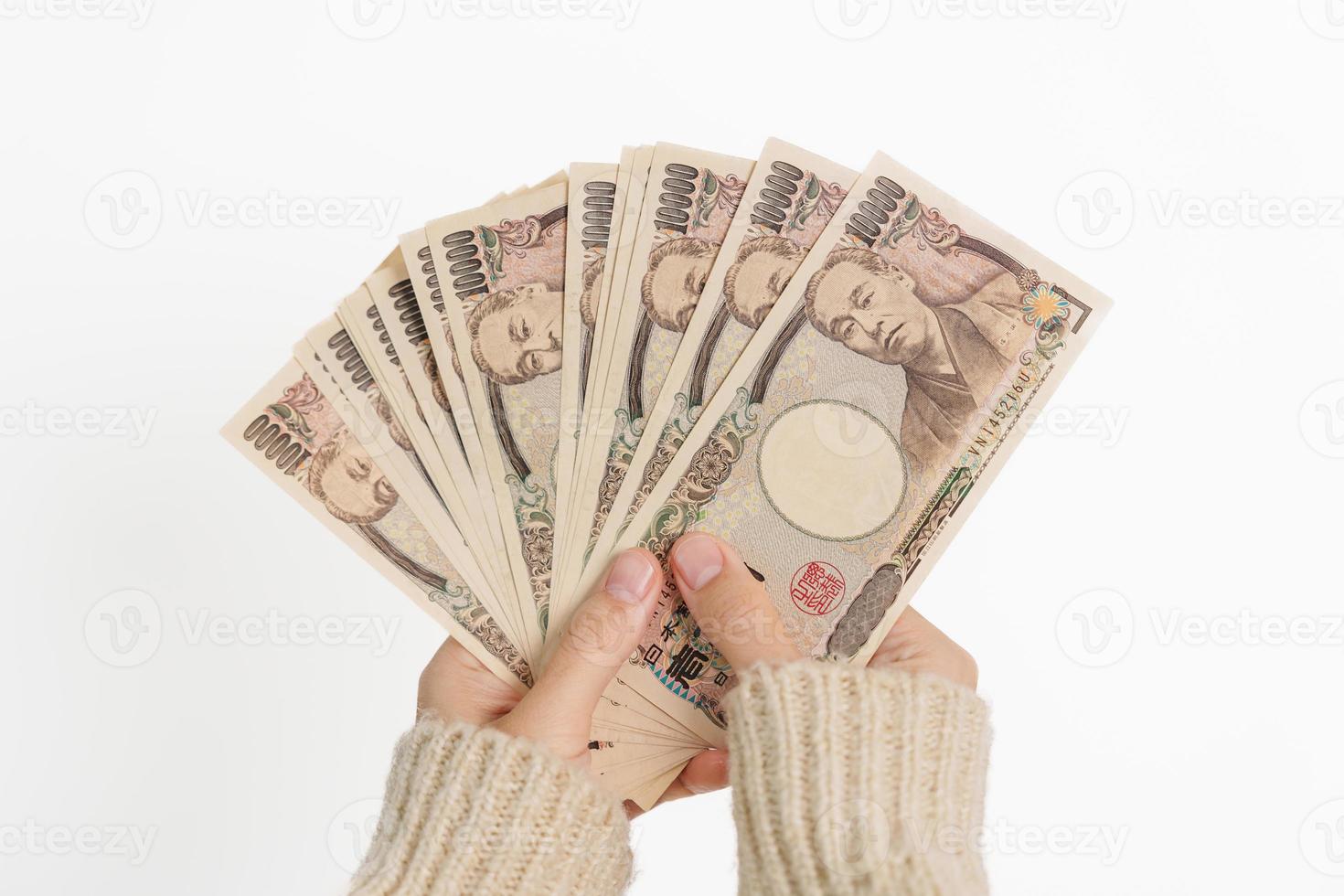 mano de mujer sosteniendo la pila de billetes de yen japonés. dinero de mil yenes. conceptos de pago en efectivo, impuestos, economía de recesión, inflación, inversión, finanzas y compras de japón foto