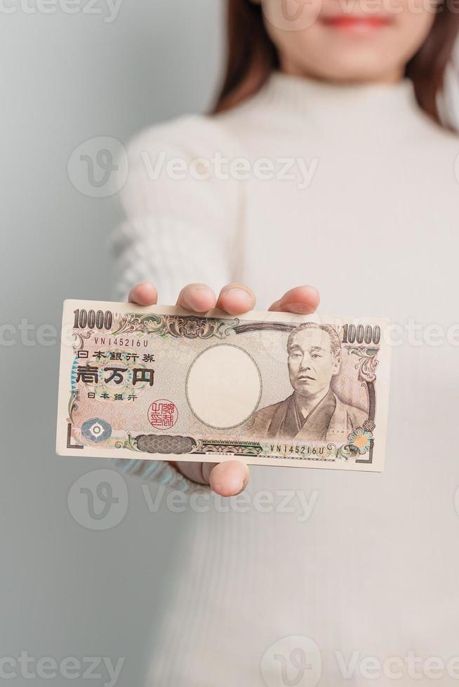 mano de mujer sosteniendo la pila de billetes de yen japonés. dinero de mil yenes. conceptos de pago en efectivo, impuestos, economía de recesión, inflación, inversión, finanzas y compras de japón foto