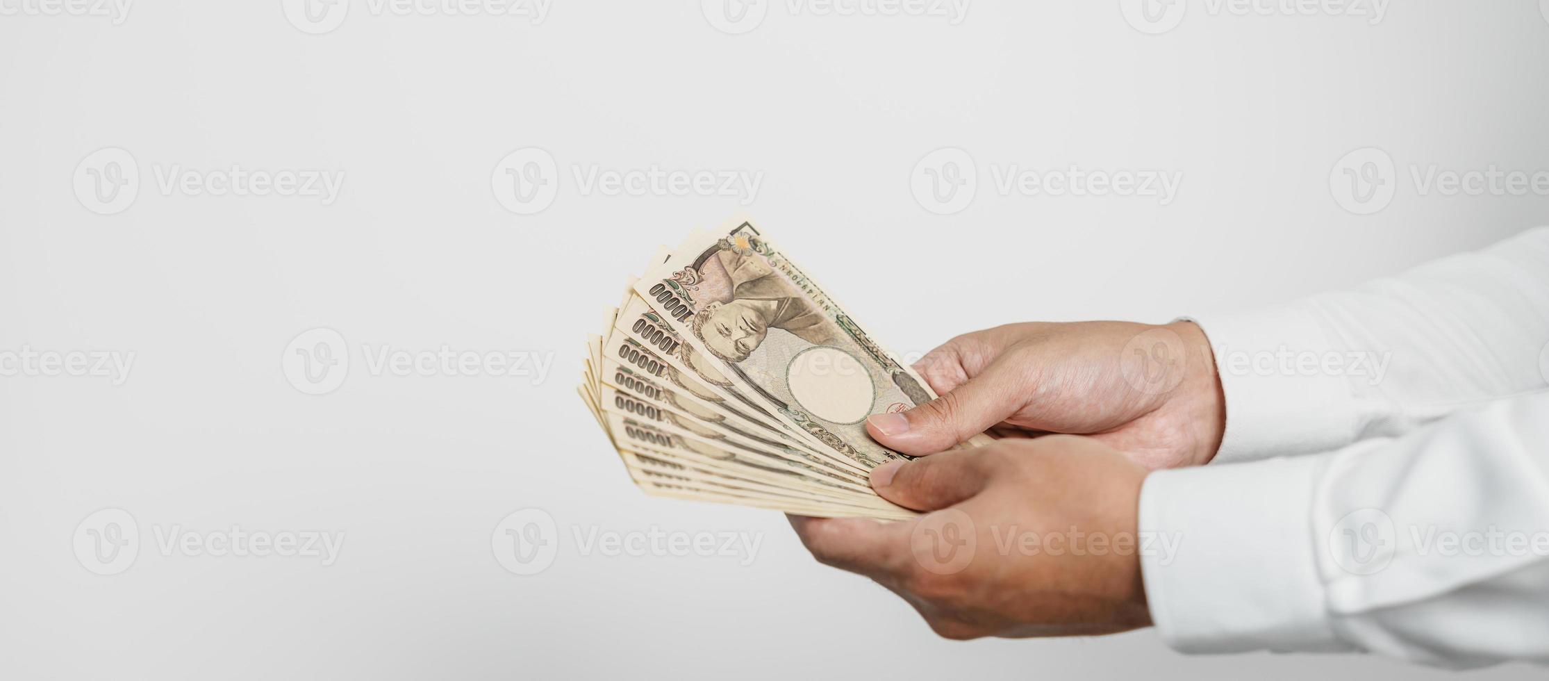 mano de hombre sosteniendo la pila de billetes de yen japonés. dinero de mil yenes. conceptos de pago en efectivo, impuestos, economía de recesión, inflación, inversión, finanzas y compras de japón foto