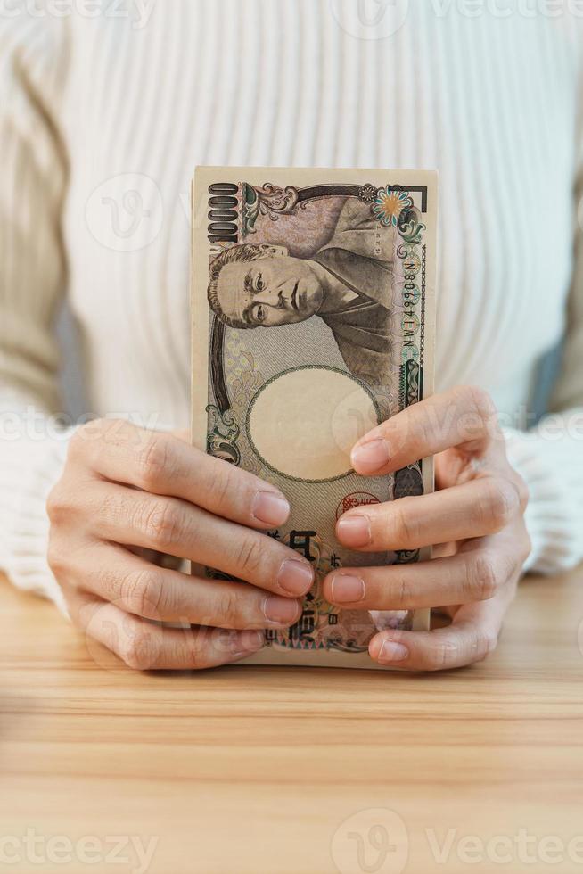 Woman hand counting Japanese Yen banknote over table background. Thousand Yen money. Japan cash, Tax, Recession Economy, Inflation, Investment, finance, savings, salary and payment concepts photo