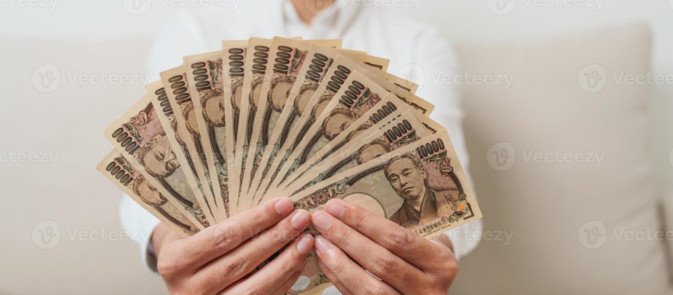 man hand holding Japanese Yen banknote stack. Thousand Yen money. Japan cash, Tax, Recession Economy, Inflation, Investment, finance and shopping payment concepts photo