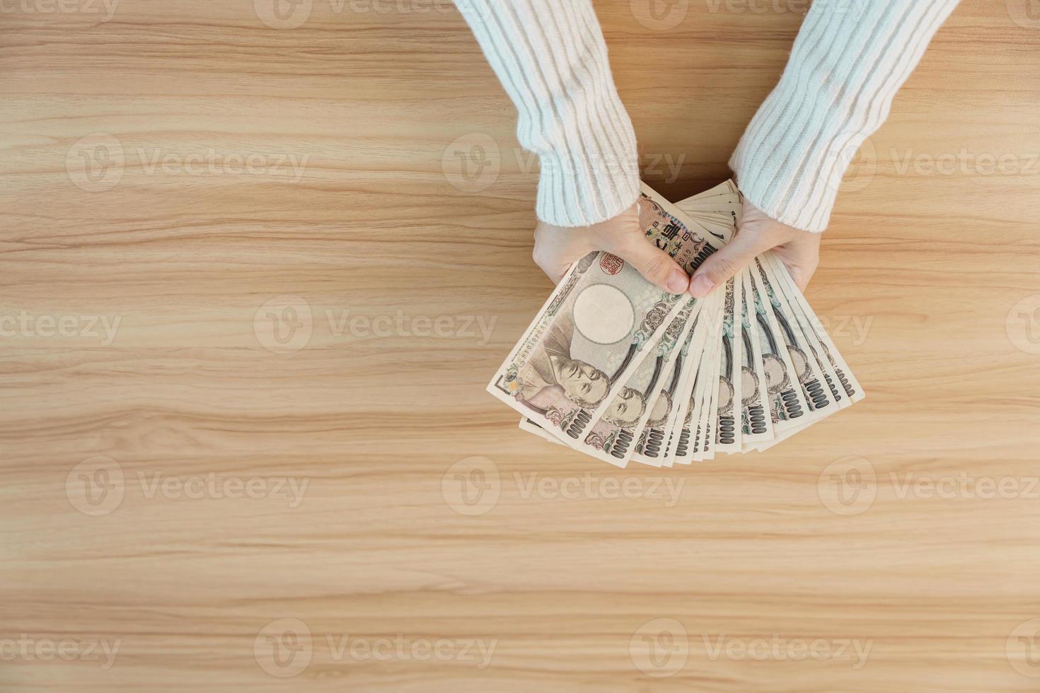 mano de mujer contando billetes de yenes japoneses sobre el fondo de la mesa. dinero de mil yenes. Japón efectivo, impuestos, economía de recesión, inflación, inversión, finanzas, ahorro, salarios y conceptos de pago foto