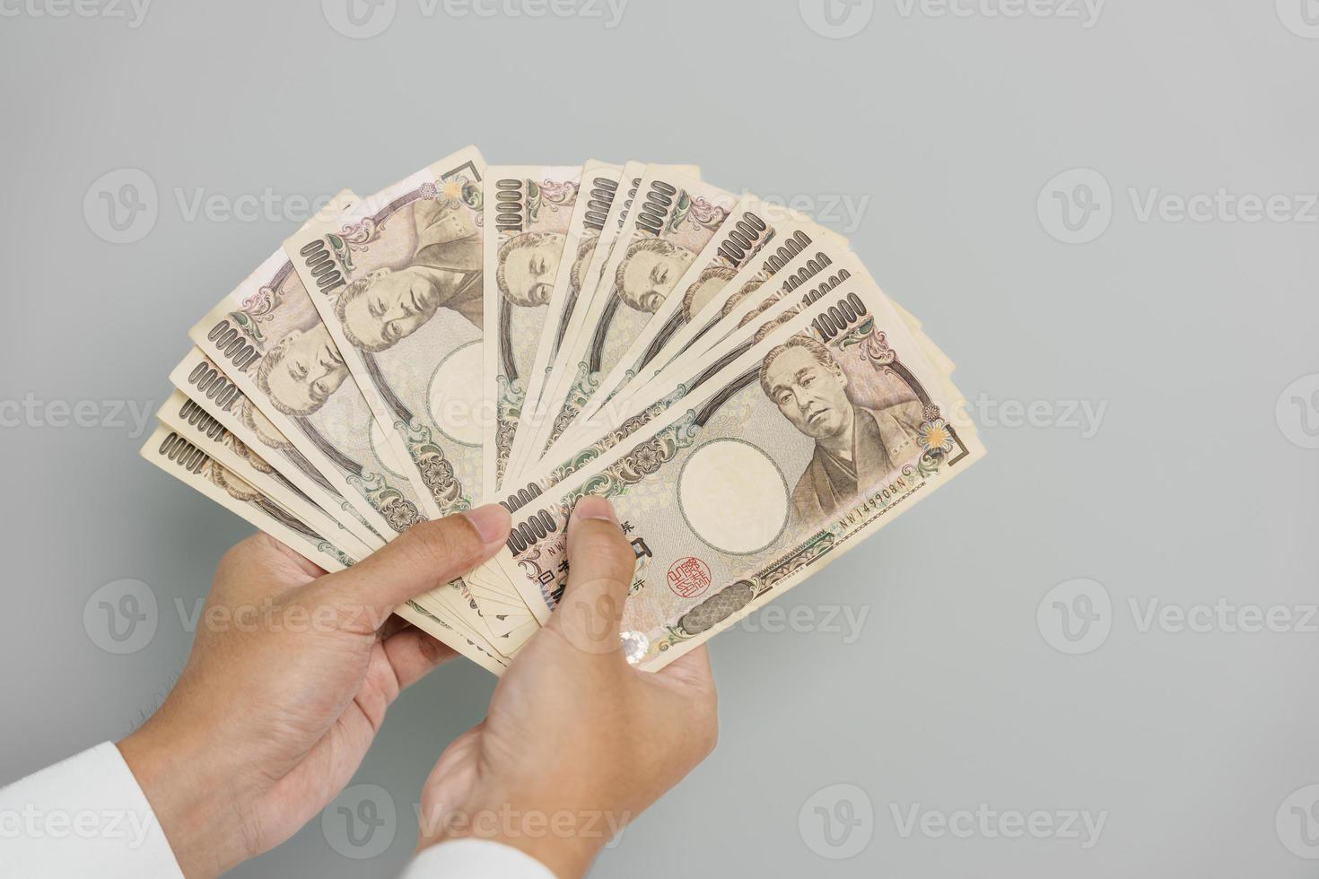 mano de hombre sosteniendo la pila de billetes de yen japonés. dinero de mil yenes. conceptos de pago en efectivo, impuestos, economía de recesión, inflación, inversión, finanzas y compras de japón foto