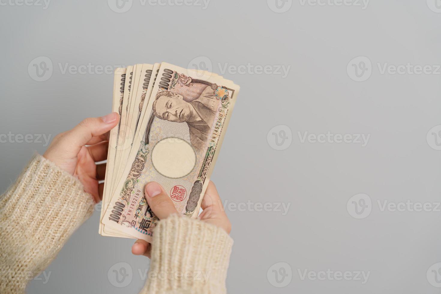 mano de mujer sosteniendo la pila de billetes de yen japonés. dinero de mil yenes. conceptos de pago en efectivo, impuestos, economía de recesión, inflación, inversión, finanzas y compras de japón foto