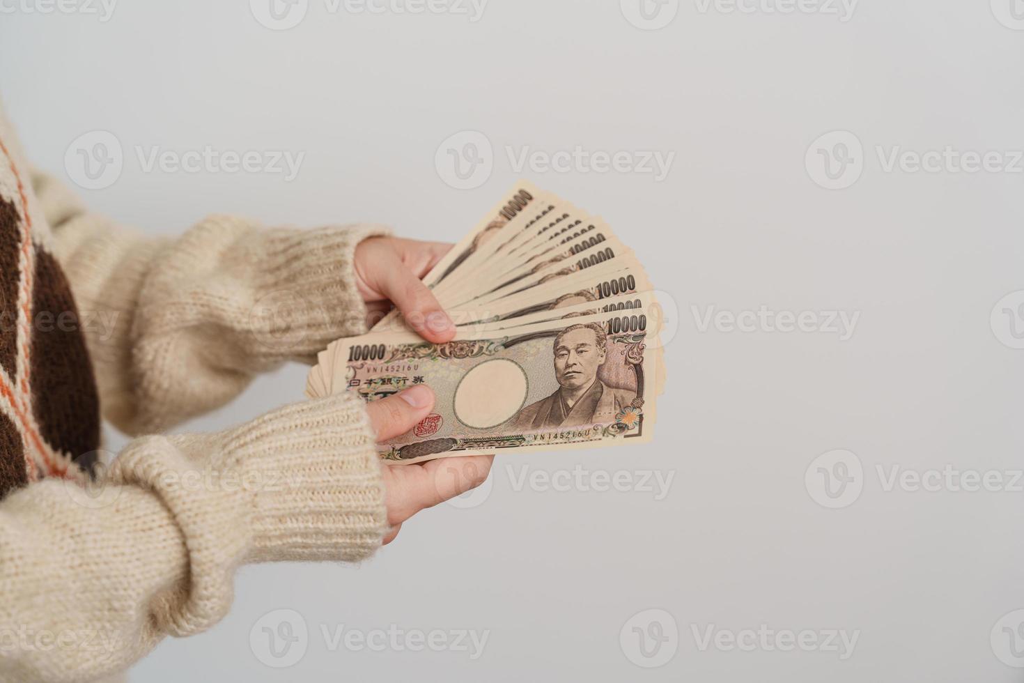 mano de mujer sosteniendo la pila de billetes de yen japonés. dinero de mil yenes. conceptos de pago en efectivo, impuestos, economía de recesión, inflación, inversión, finanzas y compras de japón foto