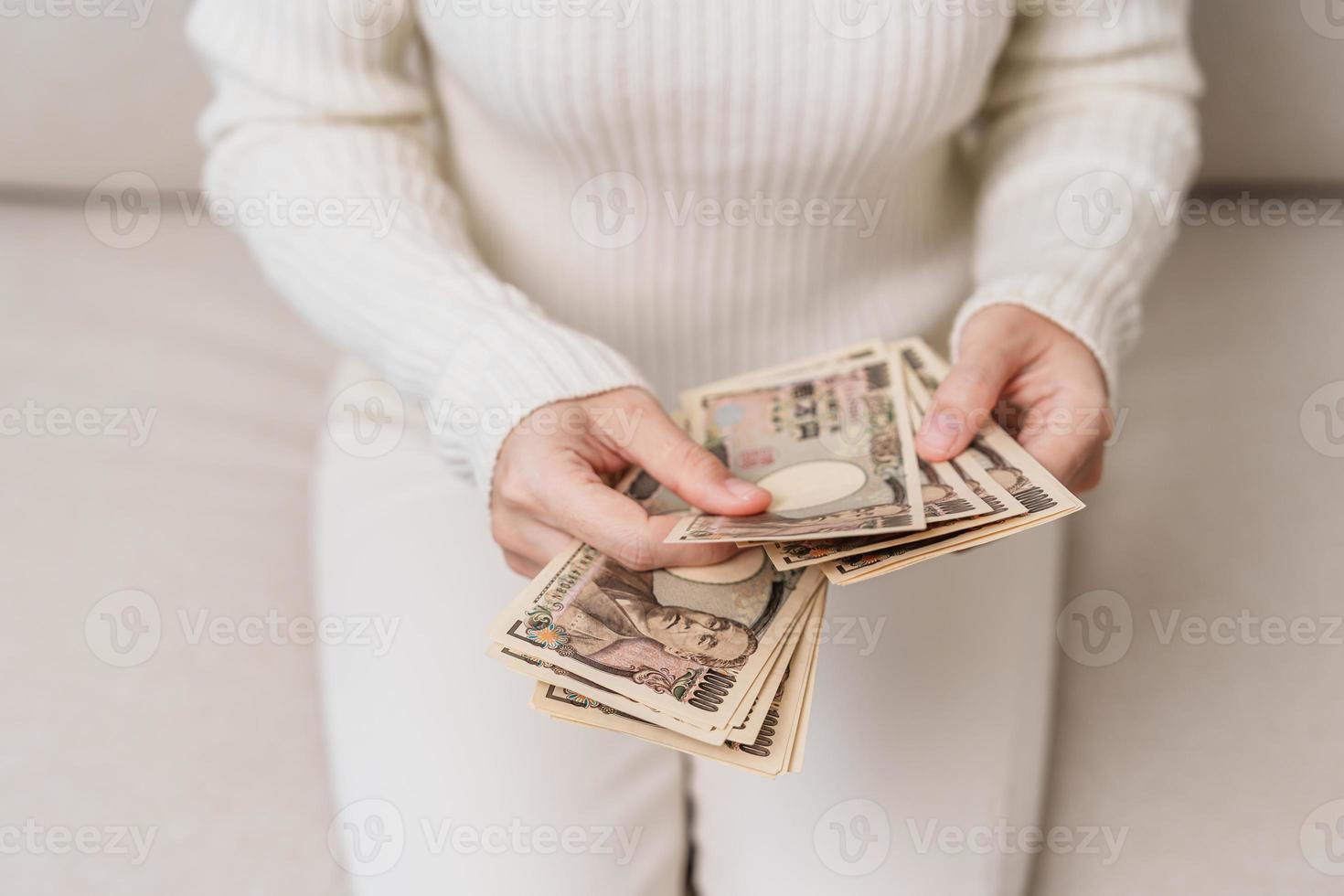 mano de mujer sosteniendo la pila de billetes de yen japonés. dinero de mil yenes. conceptos de pago en efectivo, impuestos, economía de recesión, inflación, inversión, finanzas y compras de japón foto