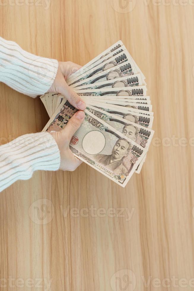 Woman hand counting Japanese Yen banknote over table background. Thousand Yen money. Japan cash, Tax, Recession Economy, Inflation, Investment, finance, savings, salary and payment concepts photo