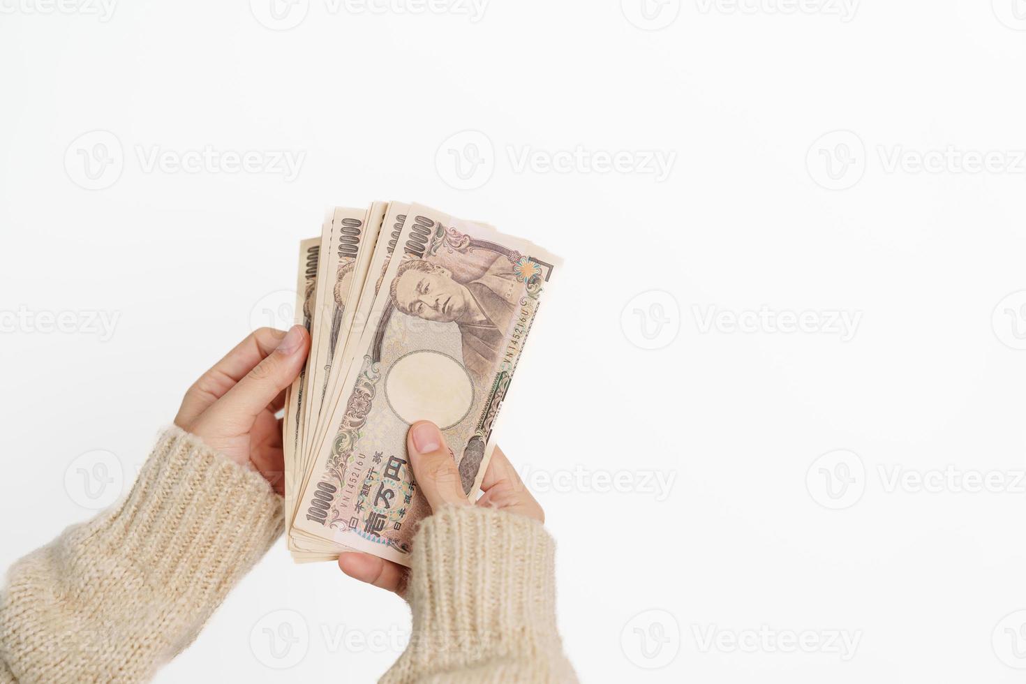 mano de mujer sosteniendo la pila de billetes de yen japonés. dinero de mil yenes. conceptos de pago en efectivo, impuestos, economía de recesión, inflación, inversión, finanzas y compras de japón foto