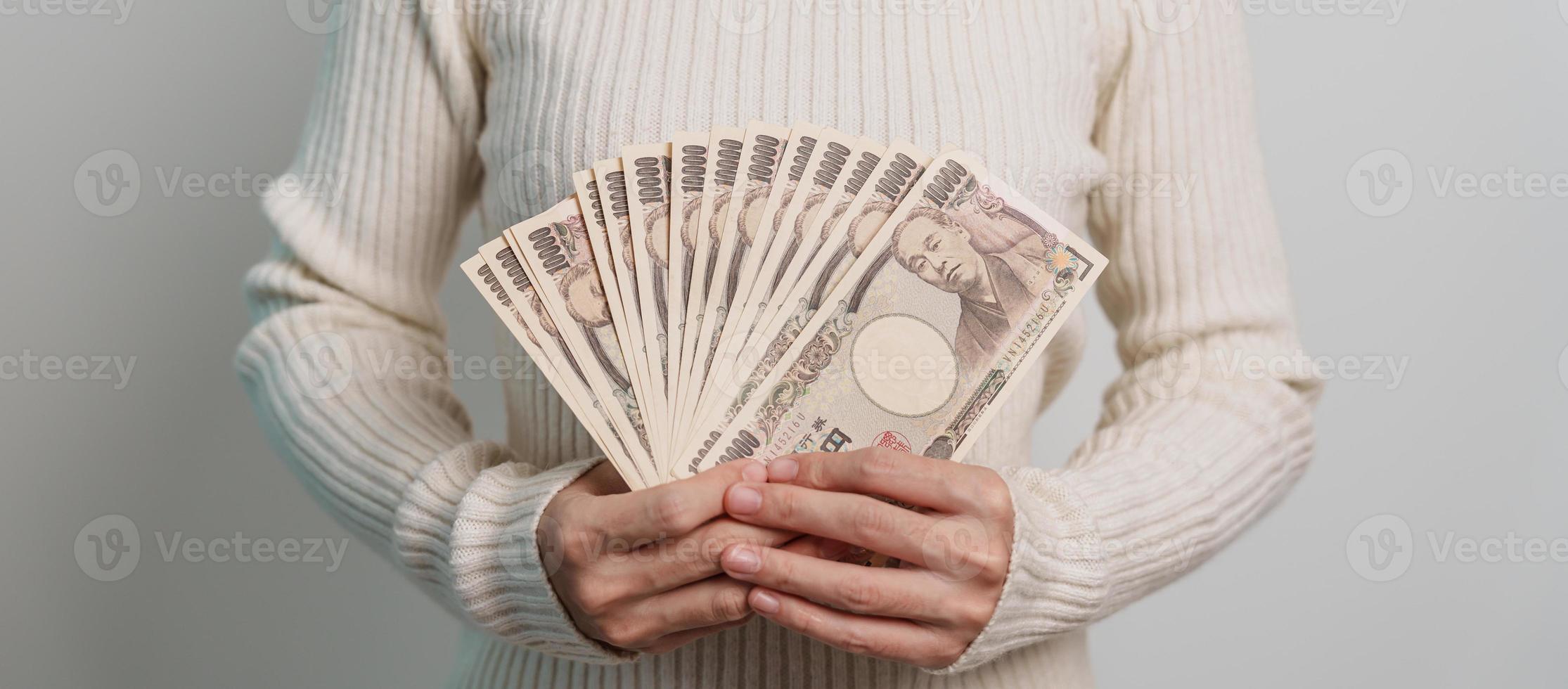 mano de mujer sosteniendo la pila de billetes de yen japonés. dinero de mil yenes. conceptos de pago en efectivo, impuestos, economía de recesión, inflación, inversión, finanzas y compras de japón foto