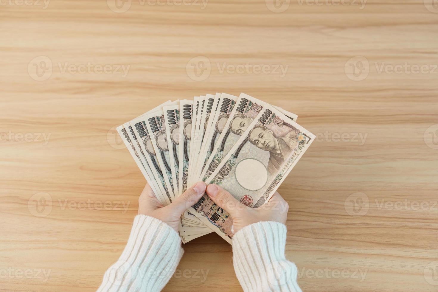 mano de mujer contando billetes de yenes japoneses sobre el fondo de la mesa. dinero de mil yenes. Japón efectivo, impuestos, economía de recesión, inflación, inversión, finanzas, ahorro, salarios y conceptos de pago foto