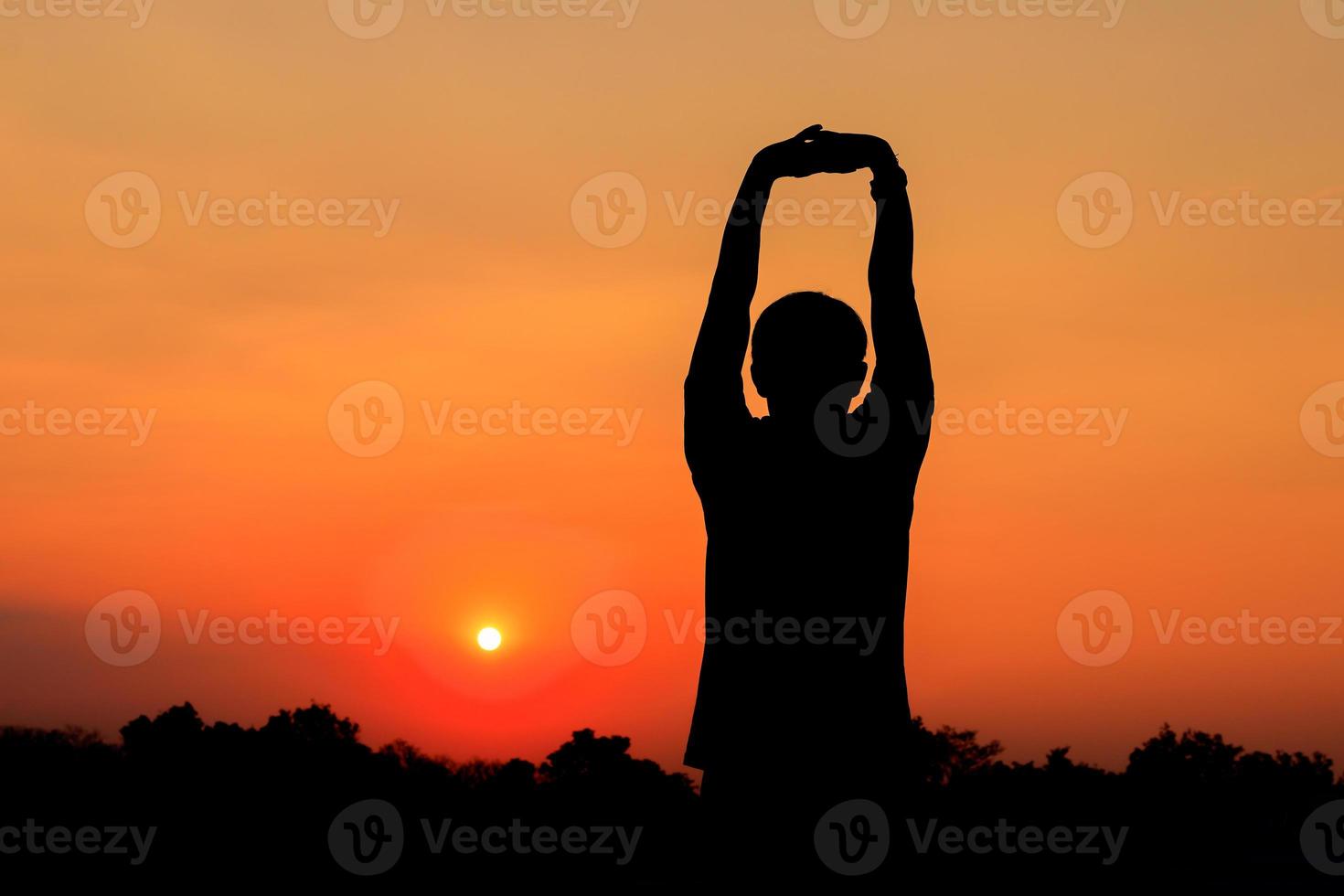 Silhouette of male meditating and yoga practicing with exercise at sunrise in public park morning photo