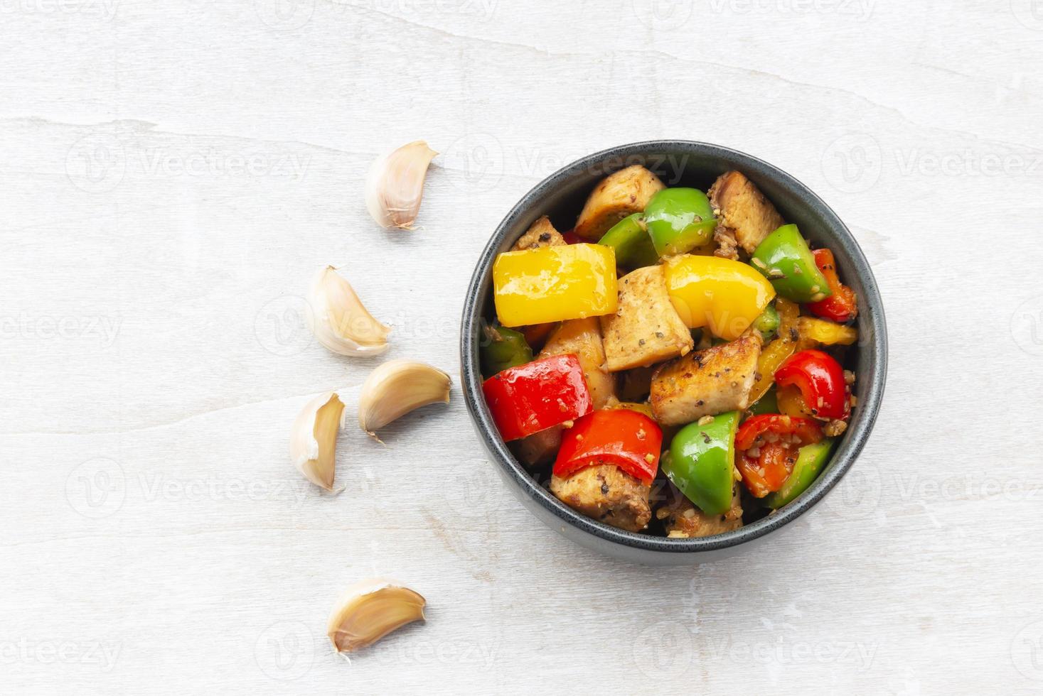 Food healthy stir fried chicken add sweet peppers in bowl on wood table. photo