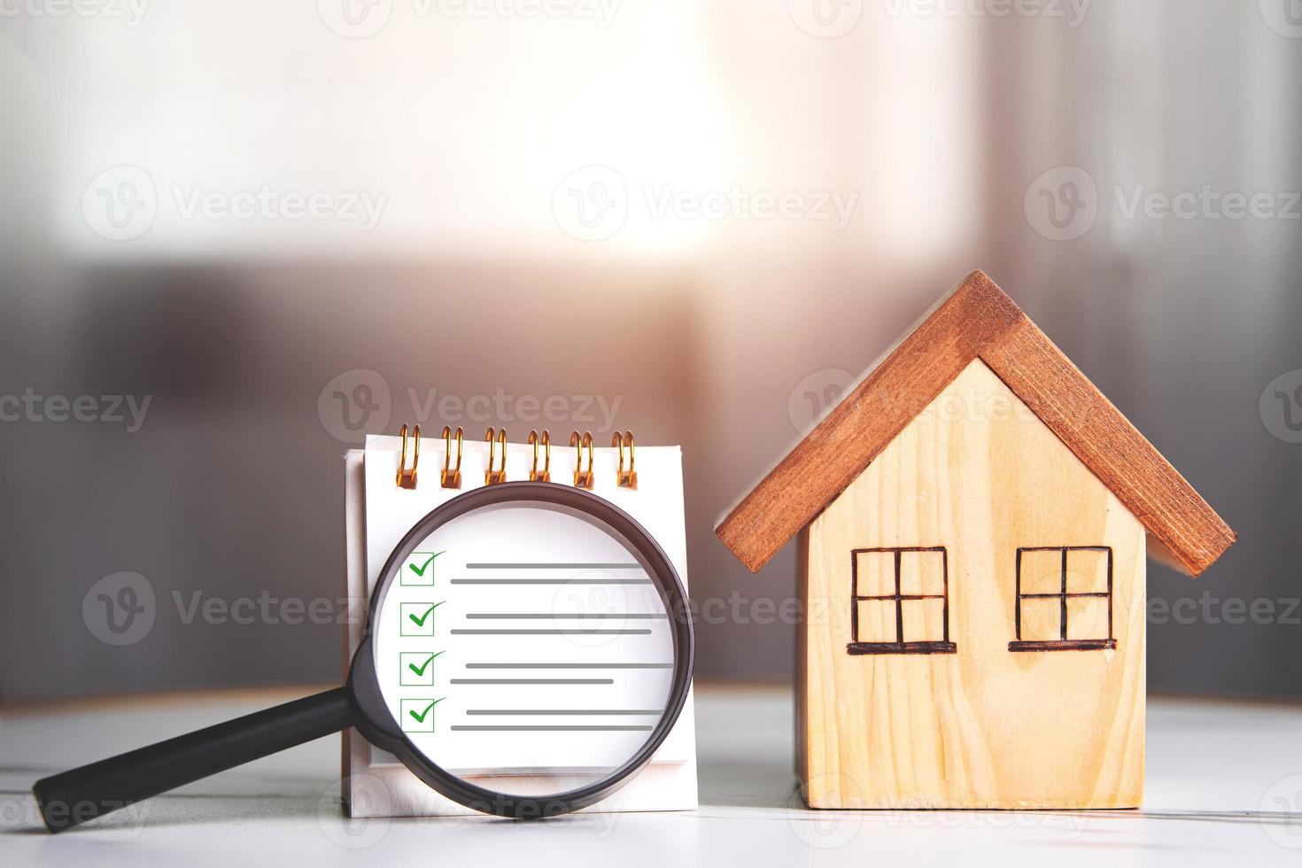 Home inspections, standards according to the requirements,  certifications, and real estate safety. Wooden house and magnifying glass with a checklist for home with copy space photo