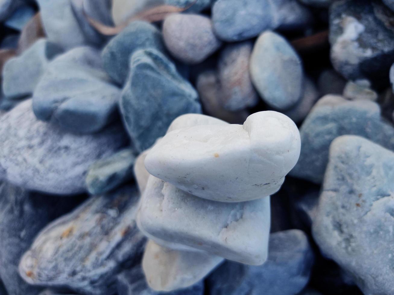 Stack of triangular stones.Group of white and colorful Stones.Pebble tower on the stones seaside.Stones pyramid on pebble beach symbolizing stability,zen,Rock,harmony,balance.Shallow depth of field. photo