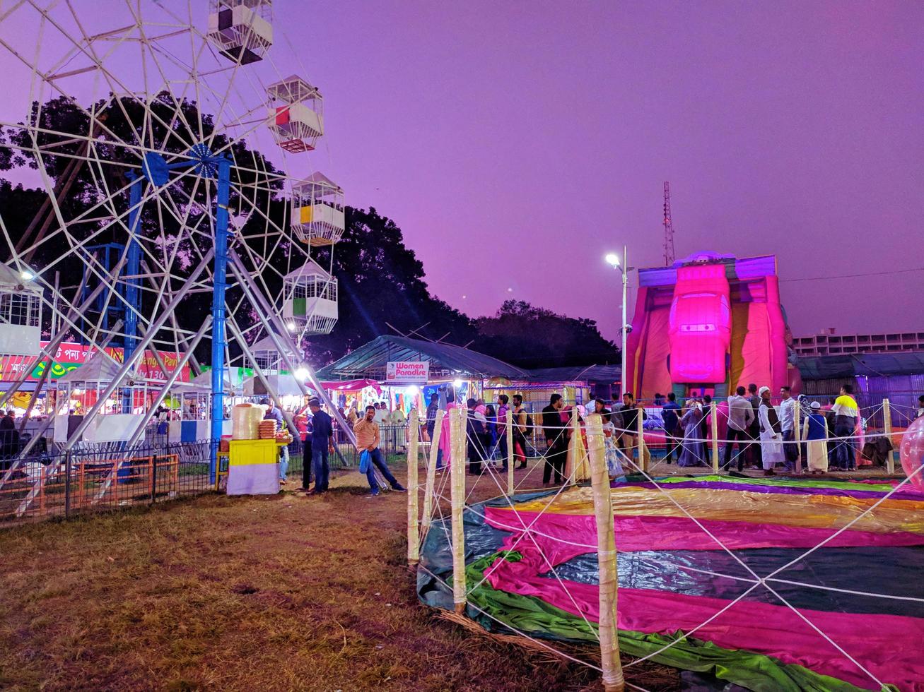 Night shot of a ferris wheel in exhibition fair.people and fairground rides at the biggest fair. Ferris Wheel at local County Fair.Colorful Trade fair in Rangpur. photo