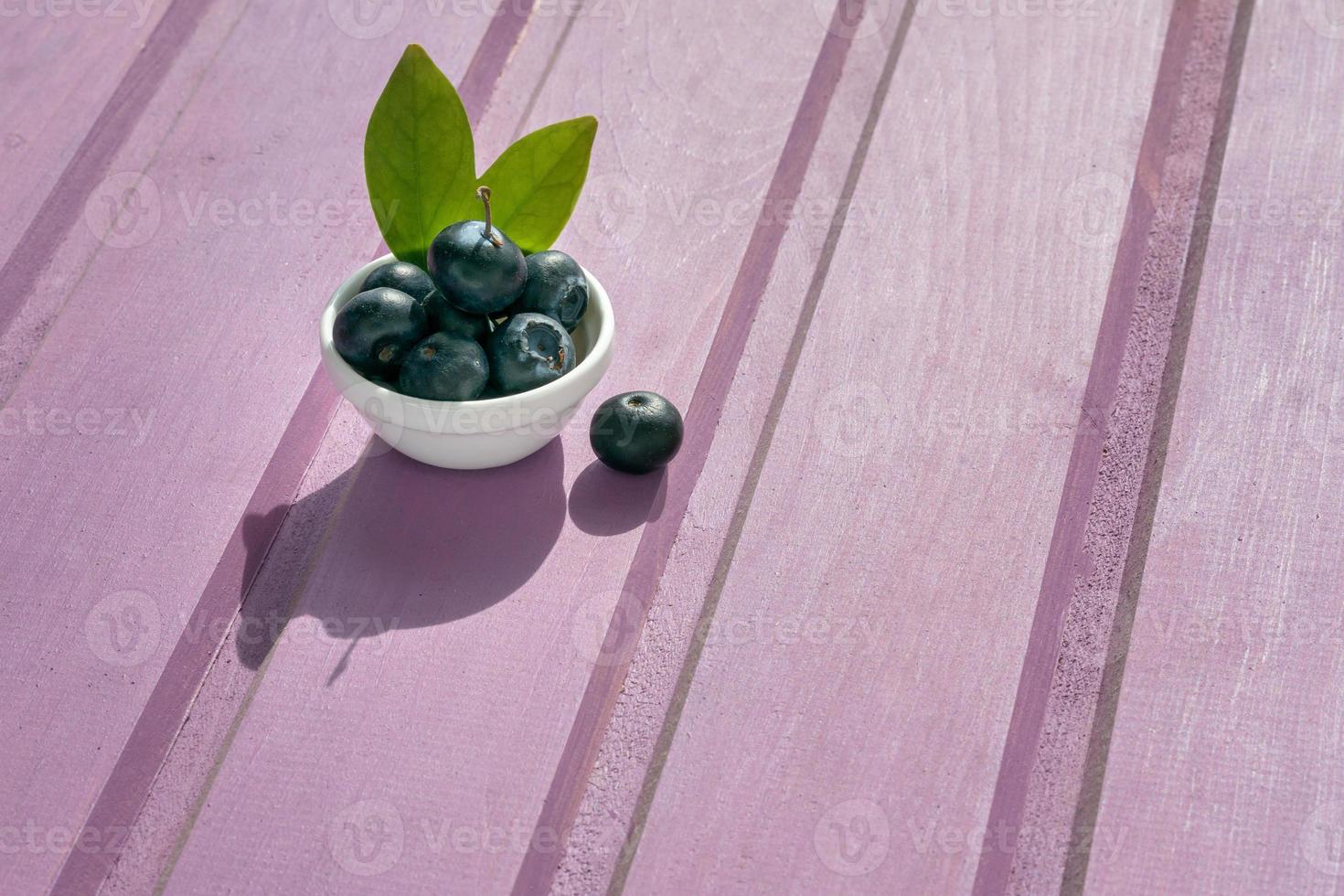 on a purple wooden background is a plate with fresh blueberries photo