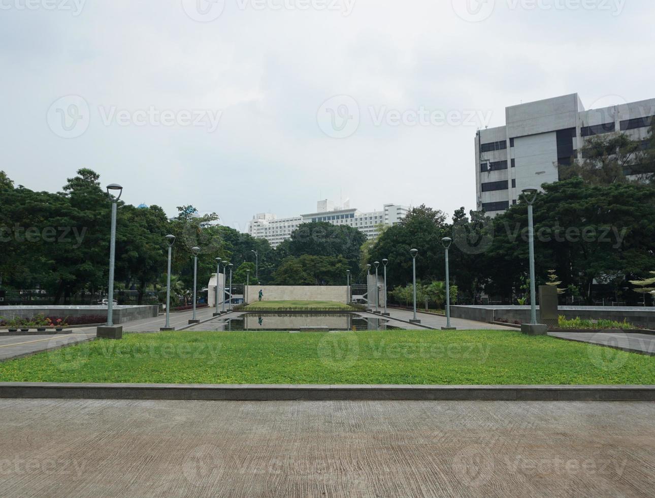 View of people watering the garden yard. This park is surrounded by greenery and several garden lampposts photo