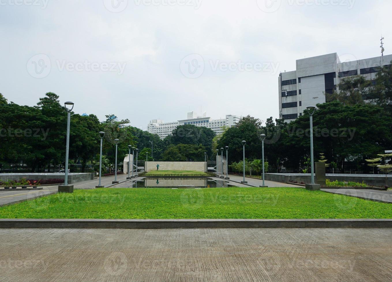 View of people watering the garden yard. This park is surrounded by greenery and several garden lampposts photo