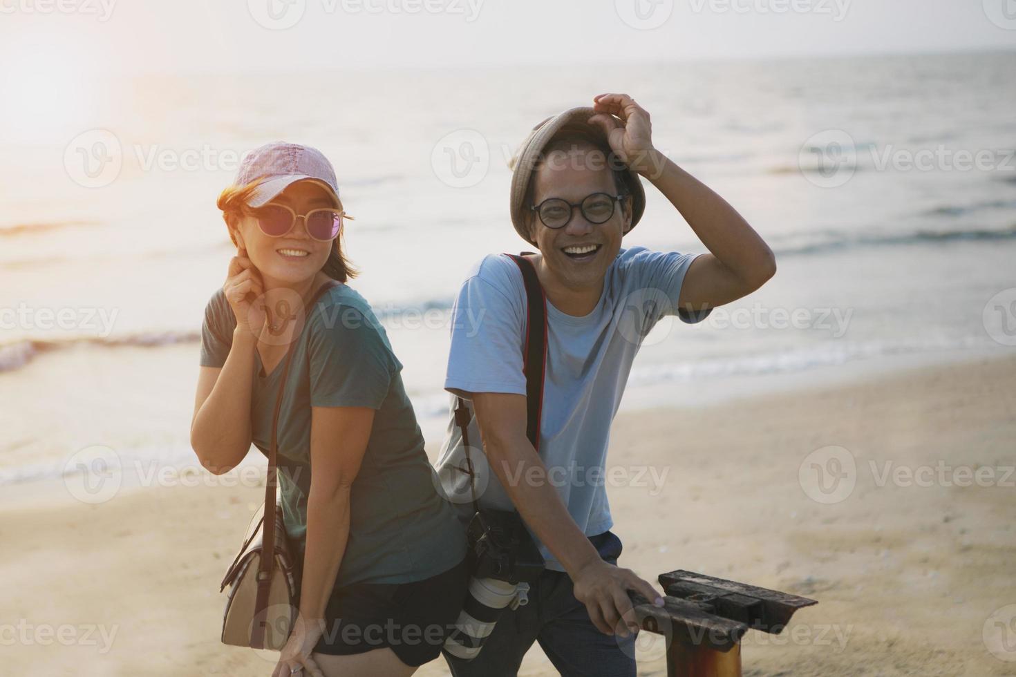 asiático parejas relajante con felicidad cara en puesta de sol playa foto